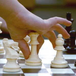 a child's hand moving a chess piece