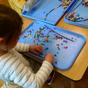 A child concentrating on a project with small beads
