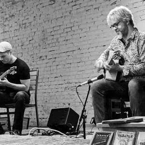 A black=and-white photo of Steve Hlavenka and Christo Ruppenthal, performing as the duo Caravan, each playing a guitar.