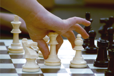 a child's hand moving a chess piece