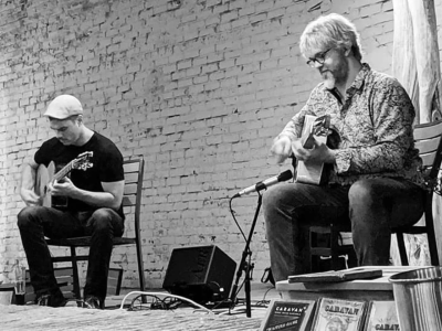 A black=and-white photo of Steve Hlavenka and Christo Ruppenthal, performing as the duo Caravan, each playing a guitar.