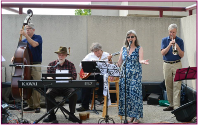 A photo of the five-person band, the Driftless Regionaires, performing outdoors.