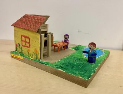 Image of a model of a house made from wood scraps and paint. 