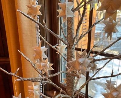 White folded paper stars hanging on bare tree branches