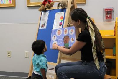 A librarian reads a story to a young child during storytime at Hawthorne Library.