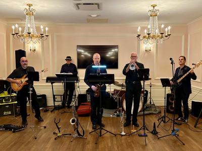 The five members of the All That Jazz Combo playing in a room with chandeliers
