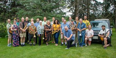 Summery outdoor photo of the 20+ members of the All That Jazz Big Band, with their instruments.